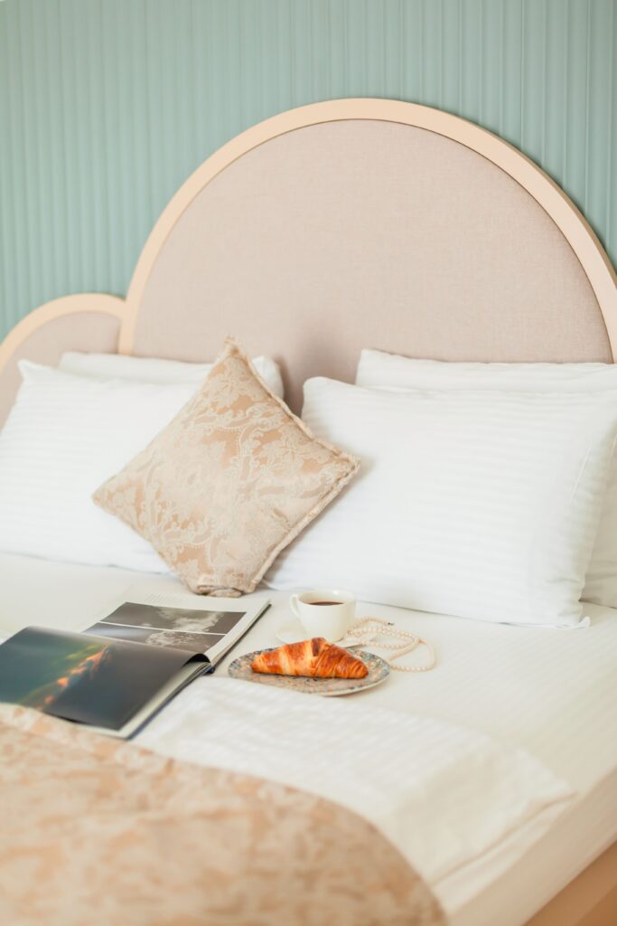 Elegant bedroom with a croissant, book, and coffee creating a relaxing morning atmosphere.